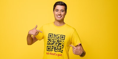 Lachender Mitarbeiter von DHL zeigt auf sein T-Shirt mit der Aufschrift Ich find's gut.